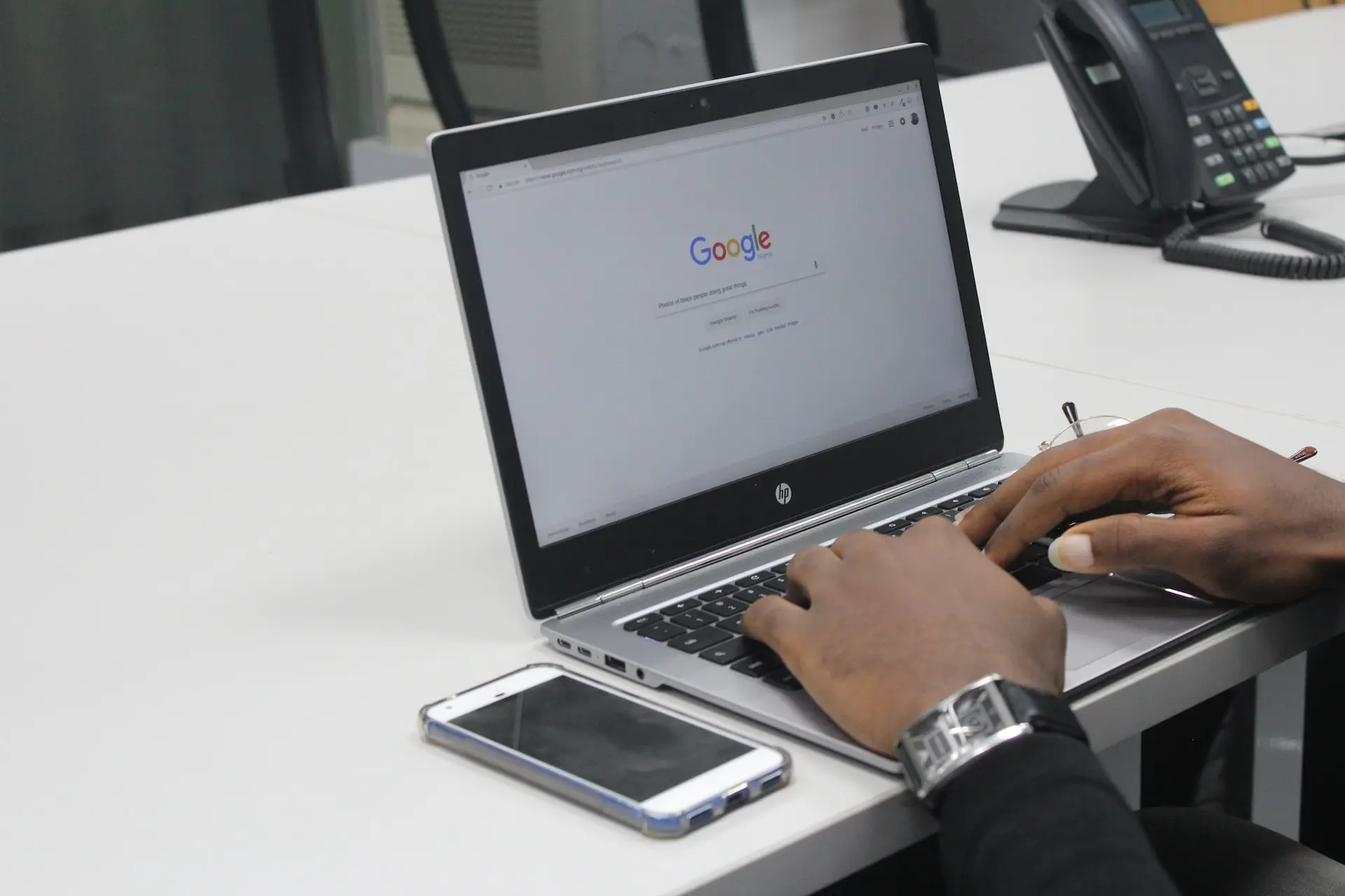 A person sitting on a desk searching on google on their MacBook