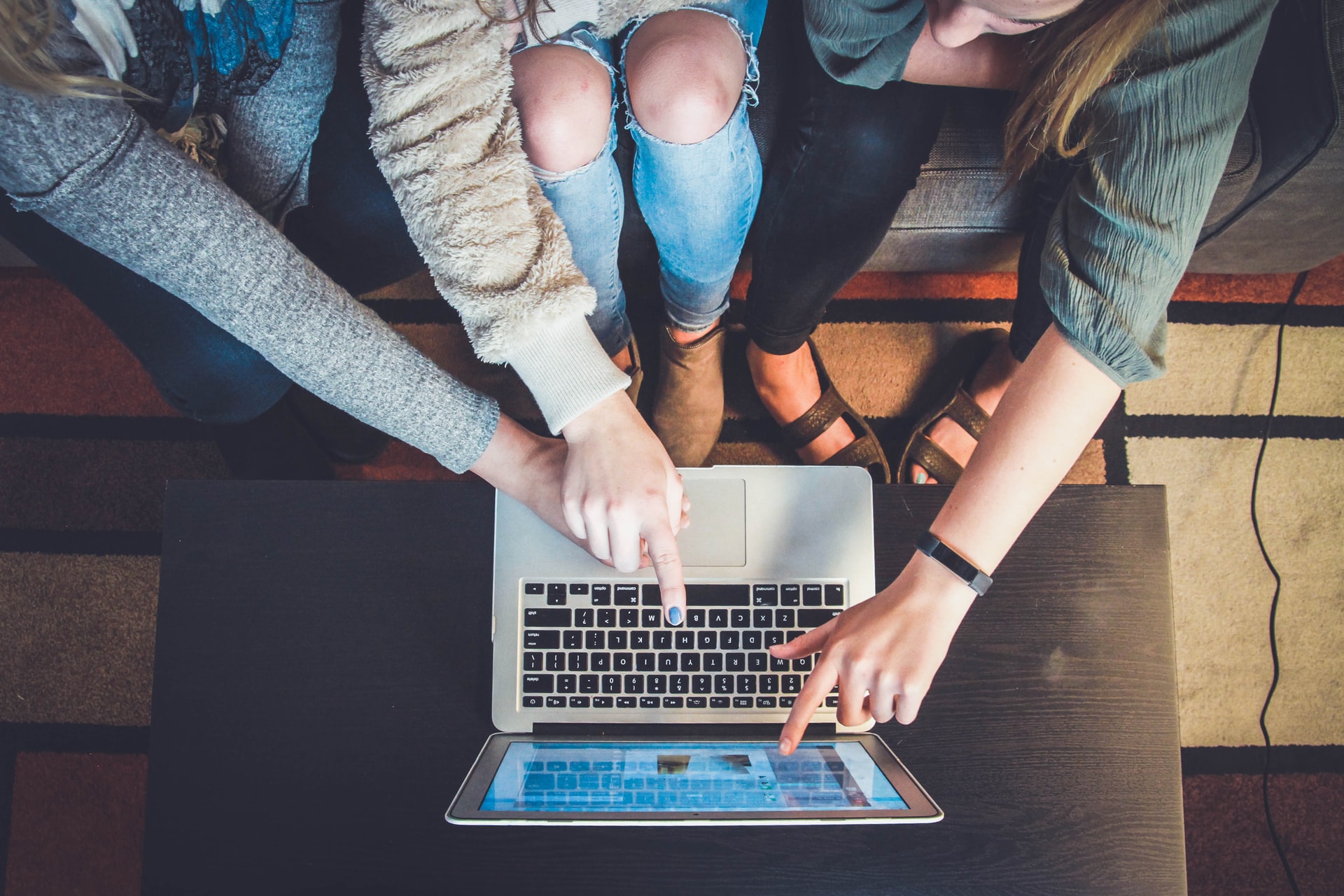 three people pointing on a laptop screen