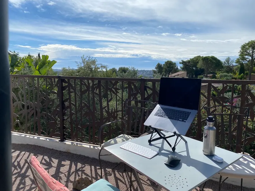 a picture of a terrace with a table having a macbook on it and a great view of the landscape